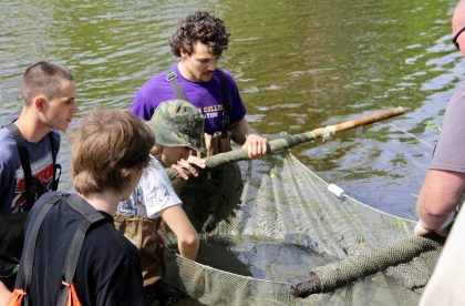 Group of Albion College community members holding a net while standing in a river