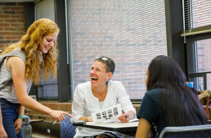 Students and faculty member conversing in a classroom setting.