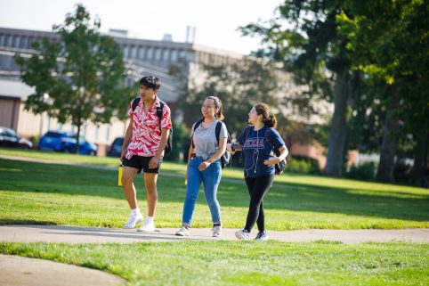 Three students walking outside on campus.