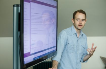 Faculty member presenting information on a digital screen in a classroom setting.