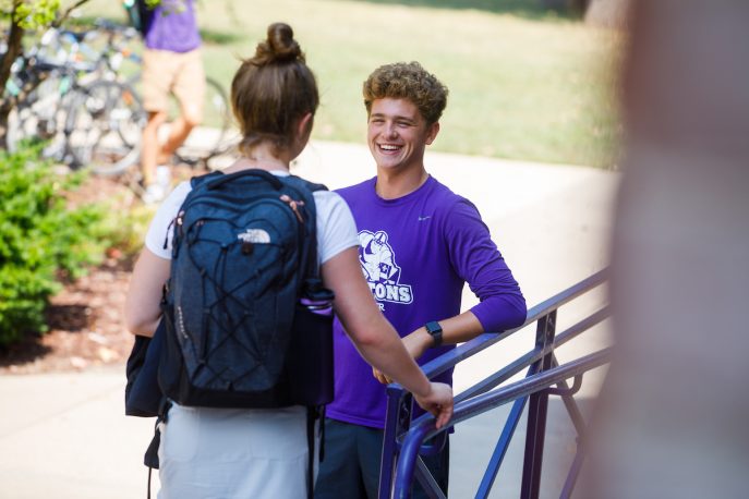 Two students standing outside having a conversation on campus.
