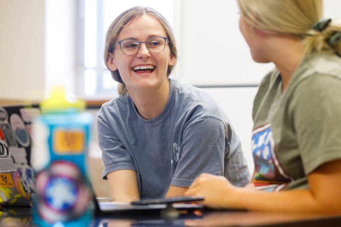 A student and professor in conversation in class.