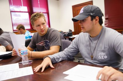 Two students conversing in a classroom setting.
