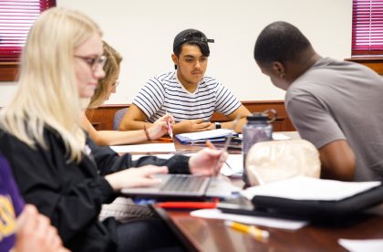 Albion students gathered around a table and working together.