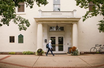 Student walking in front of Samuel Dickie Hall.