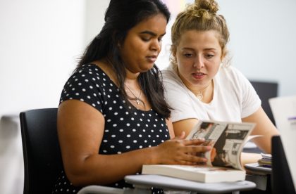 Two students sitting together reading a book together