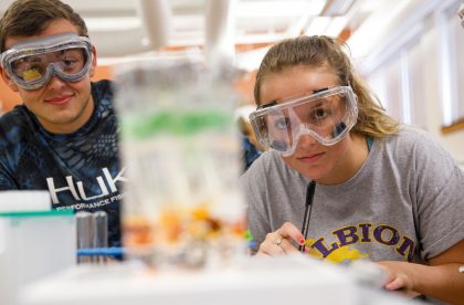 Two Albion students wearing protective goggles in a lab setting.