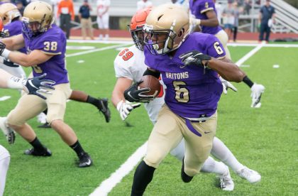 Member of the Albion College football team running with a football during a game.