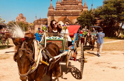 Two students abroad posing on a horse-drawn carriage.