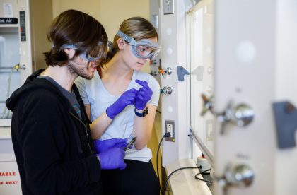 Two students wearing protective goggles in a lab setting.