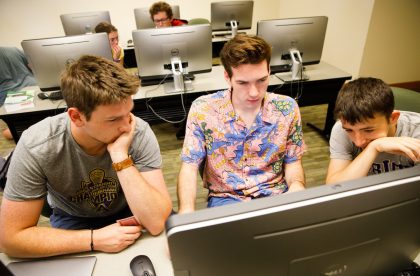 Three students working together in a computer lab.