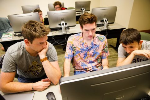 Three students working together in a computer lab.