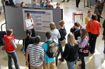Students listening to a poster presentation in the Science Atrium.