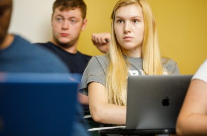 A student sitting in the classroom working on their laptop.