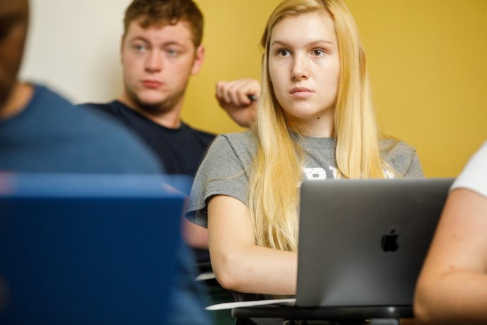 A student sitting in the classroom working on their laptop.