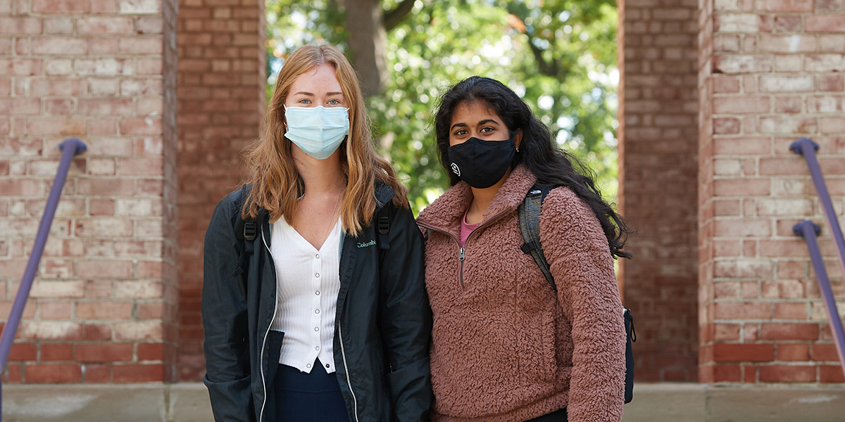 Two Albion College students wear face masks outside Baldwin Hall.