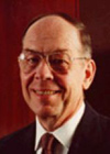 Man wearing a suit and glasses, smiling.