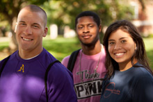 Three students standing next to each other, smiling.