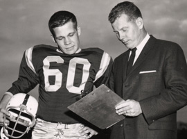 A man wearing a football uniform standing next to a man wearing a suit.
