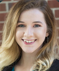 A headshot of a smiling student in front of a brick wall.