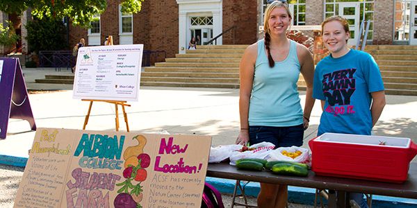 Students standing behind a table with produce on it.