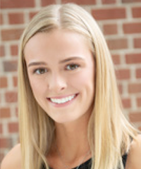 A headshot of a smiling student in front of a brick wall.