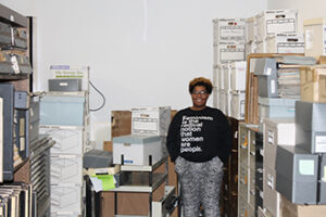 A student standing in a storage room filled with boxes.