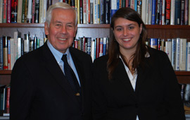A student stands next to Senator Richard Lugar in front of a bookcase.