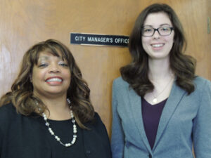 A student standing next to a woman in front of a door that says: "City Manager's Office"