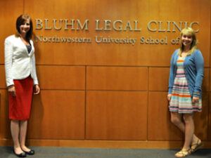 Two people standing in front of a wall that reads: "Bluhm Legal Clinic"