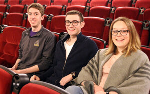 Three students sitting in an auditorium.