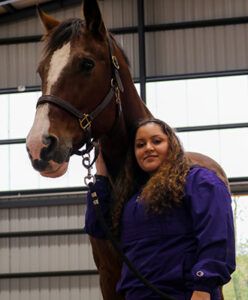 A student posing with a horse.