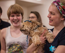 Two students, one of them holding a dog in a yarmulke.