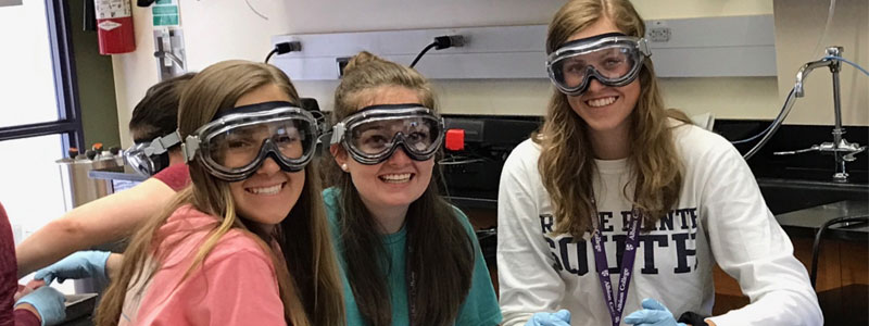 Three girls wearing goggles and posing for the camera