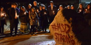 Students holding candles surrounding the Albion College Rock.