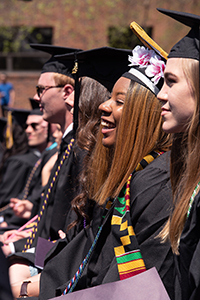 Students sitting in a row in caps and gowns at commencement.