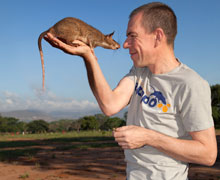 A man holding a rat up to his face.