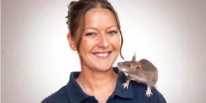 A smiling woman with a rat on her shoulder.