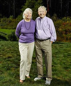 Two people wearing purple shirts smiling at the camera.