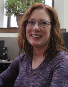 A person in a purple shirt smiling at the camera.