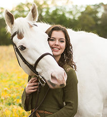 A student standing next to a horse.