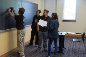 Students writing on a chalkboard.