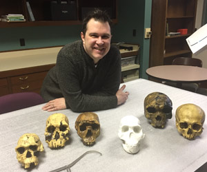 A man poses with 3D printed skulls.