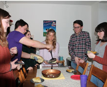 A group of students standing around a dinner table.