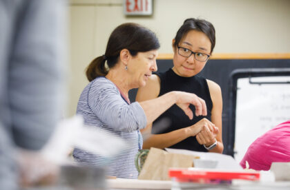 A student and faculty member in conversation in the ceramics studio.