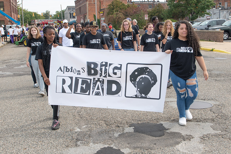 Students walking in a parade carrying a Big Read banner.