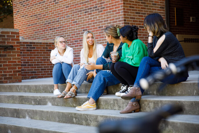 A group of students in conversation on the steps of Olin.