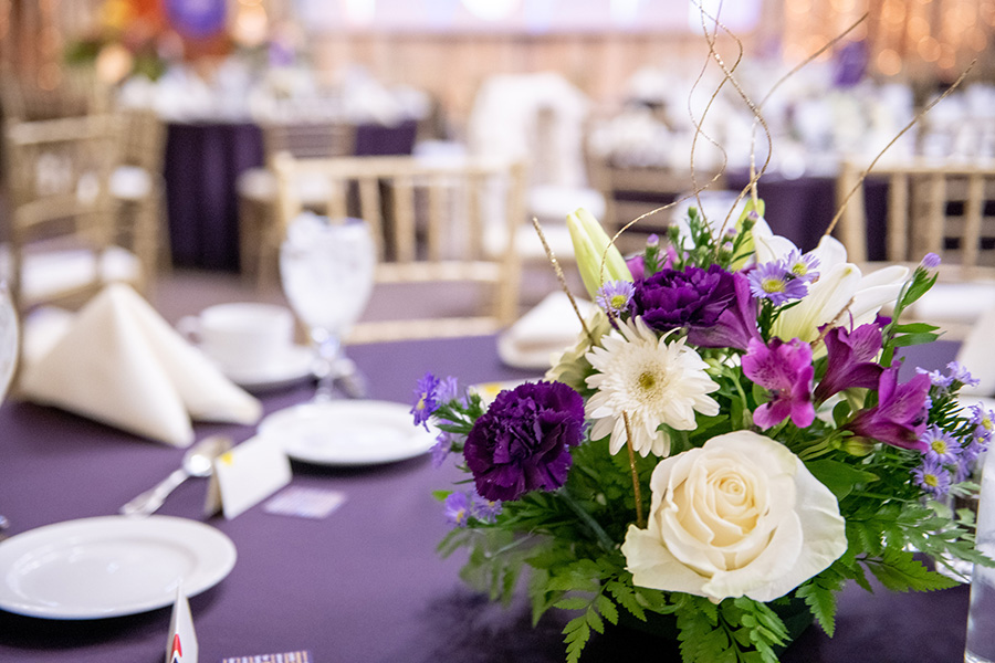 A table decorated with flowers and a purple tablecloth.