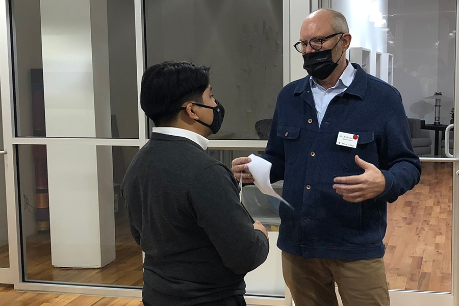 Two people wearing masks talking to each other.