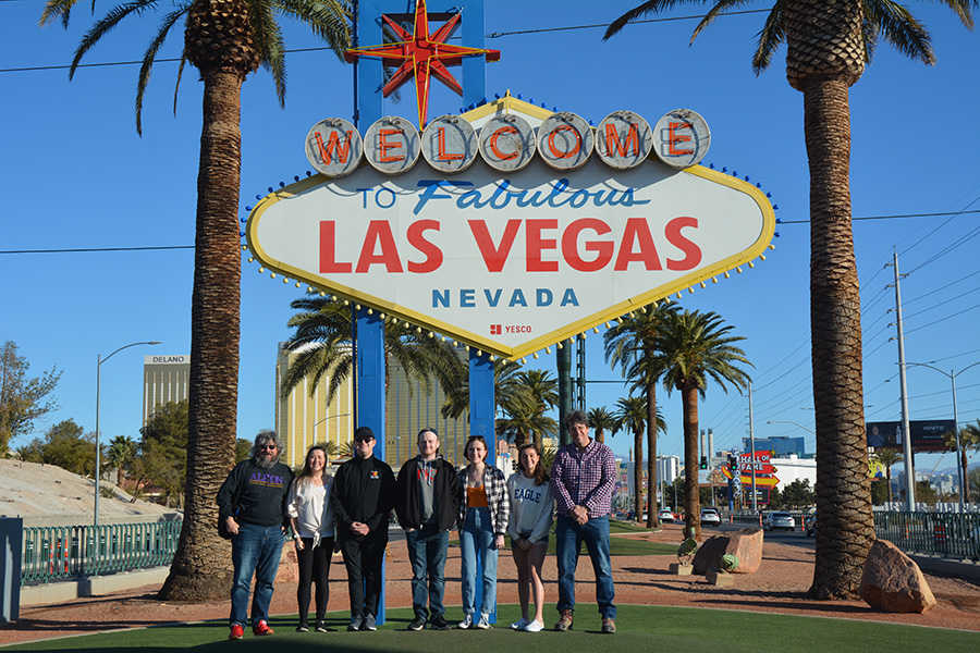 Students and faculty posing in front of a Las Vegas sign.
